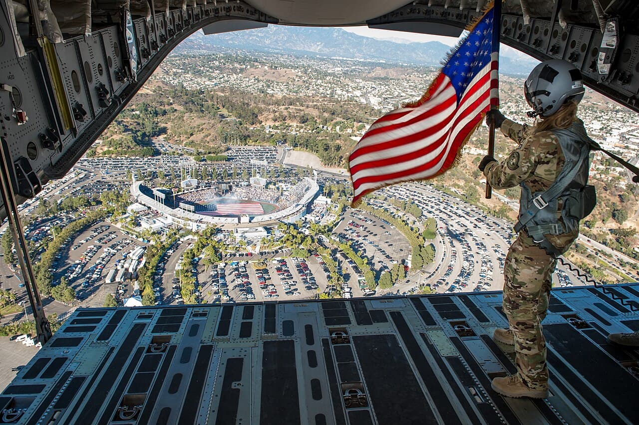 Staff Sgt. Kori Myers, 418th Flight Test Squadron load master, waves the American flag out of the back of a C-17…